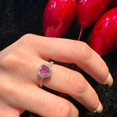 Anello solitario con zaffiro rosa a Cuore e diamanti bianchi che avvolgono la pietra centrale e il gambo.